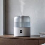 White smart humidifier emitting mist on a bedroom cabinet